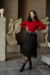 a lady wears a red round neck sweater with a black midi tulle skirt